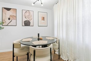 A dining area with a round table, four chairs, and three framed artworks on the wall. - KingBeds+Base10min+Hwy84+ChefKitchen+Spa Showers (Hinesville)