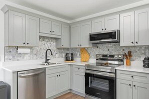A modern kitchen with white cabinetry, a stainless steel dishwasher, a built-in oven, and a microwave. - KingBeds+Base10min+Hwy84+ChefKitchen+Spa Showers (Hinesville)