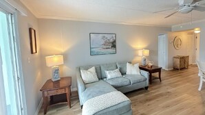 Ein Wohnzimmer mit einer Couch, zwei Beistelltischen, einer Lampe und einem Bild an der Wand.