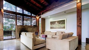 A modern living room with a fireplace, two sofas, and a large window overlooking greenery.