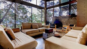 A spacious living area with large windows, a fireplace, and a cozy seating arrangement.