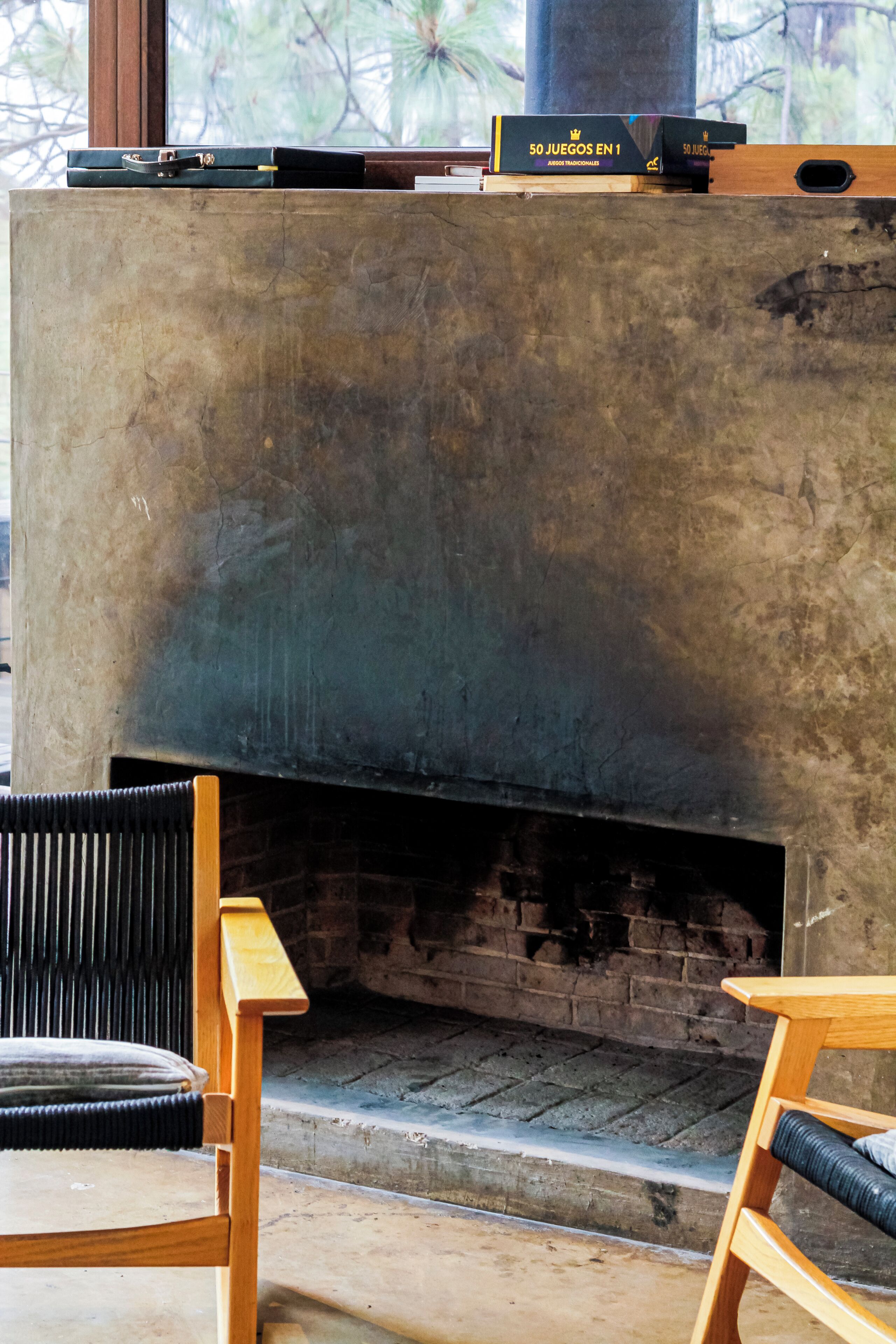 Una chimenea con revestimiento de ladrillo, un banco de madera y una mesa con libros.