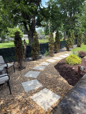 A garden pathway with stepping stones, surrounded by trees and shrubs.