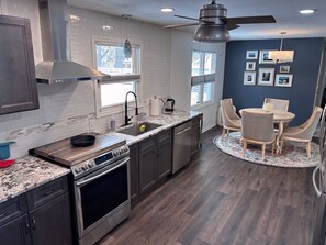 A modern kitchen with a built-in oven, a sink, and a dining area with a round table and chairs.