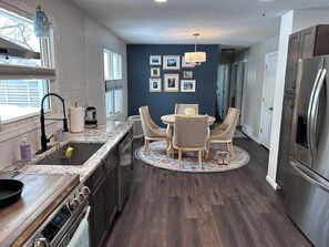 A modern kitchen with a dining area, stainless steel appliances, and a blue accent wall.