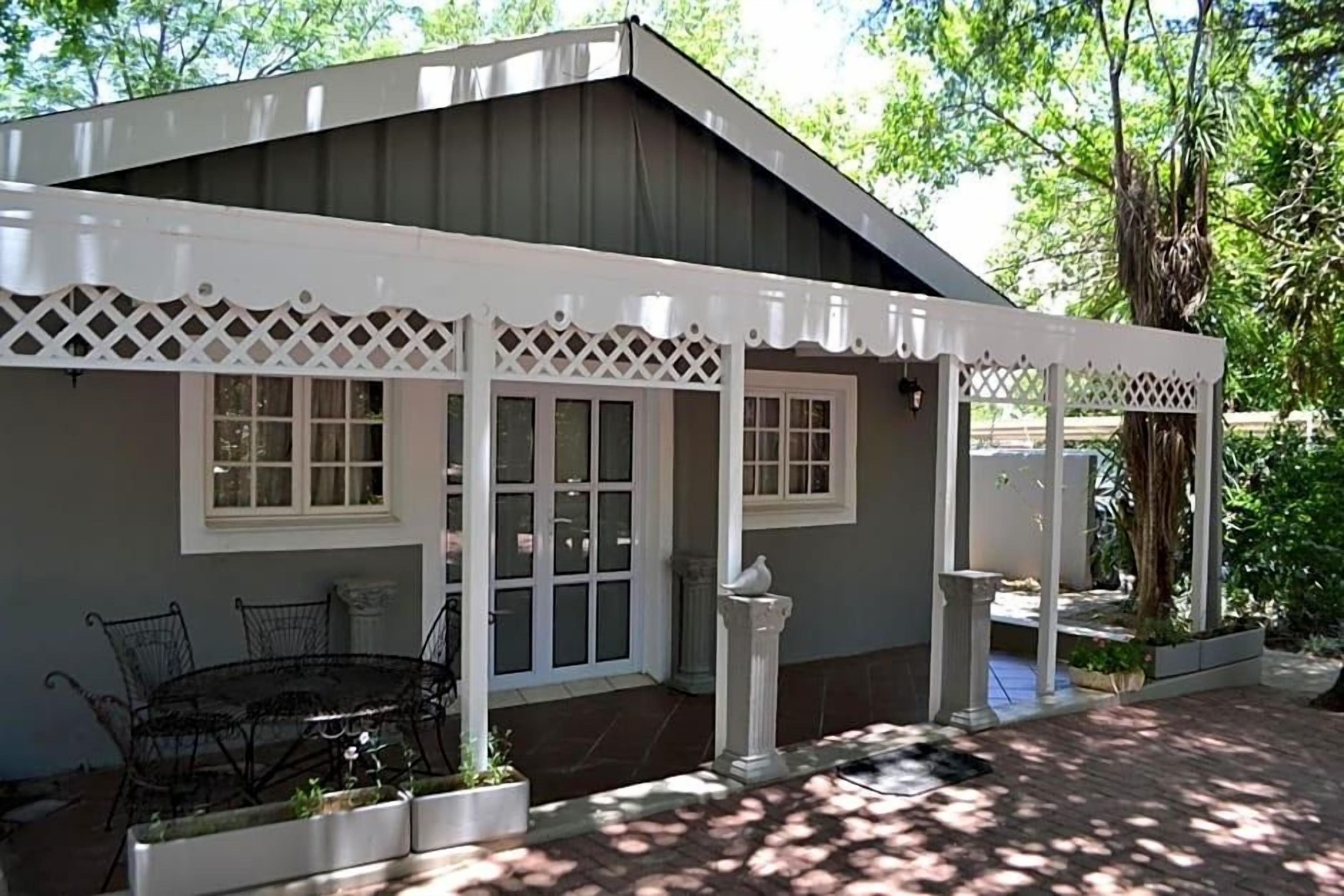 A house with a covered patio, a dining table with chairs, and a small garden area.