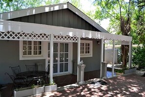A house with a covered patio, a dining table with chairs, and a small garden area. - Hobbit Boutique Hotel (Bloemfontein)