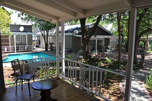 A covered outdoor area with a pool, a table, and chairs. - Hobbit Boutique Hotel (Bloemfontein)
