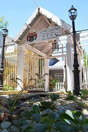 A gazebo-style structure with a sign reading 'Hobbit' and a phone number. - Hobbit Boutique Hotel (Bloemfontein)
