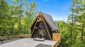 A cabin with a triangular roof, a front door, and a small porch area. - Luxury A-Frame w/ Hot Tub (Sevierville)