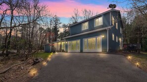 Ein modernes, zweistöckiges Haus mit Auffahrt, umgeben von Bäumen.