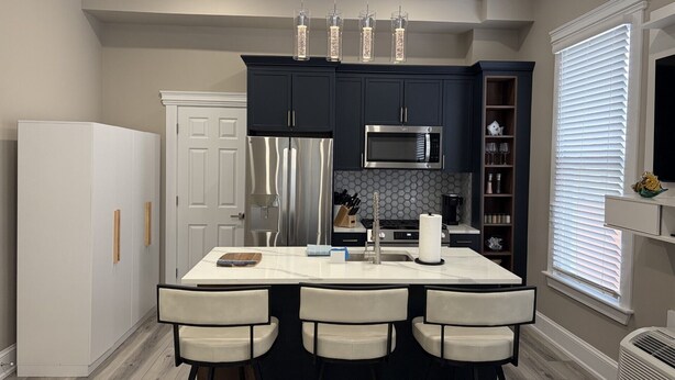 Una cocina moderna con una isla central, electrodomésticos de acero inoxidable e iluminación colgante.