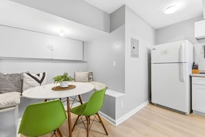 Una cocina moderna con un refrigerador blanco, una mesa de comedor con sillas verdes y una planta en maceta sobre la mesa.