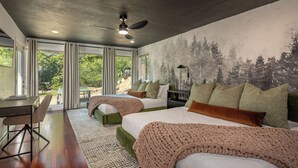 Ein Schlafzimmer mit zwei Betten, einem Schreibtisch und Blick ins Freie.