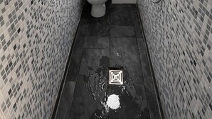 Une petite salle de bain carrelée, équipée de toilettes, d’une douche et d’une fenêtre.