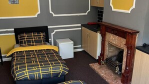 Une chambre avec deux lits, une petite kitchenette et une cheminée.