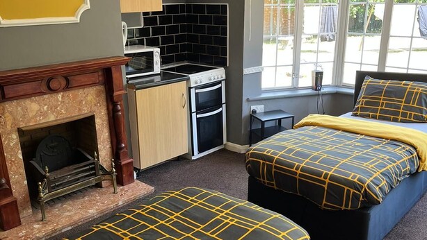 Une chambre avec deux lits, une cheminée, un coin cuisine et une vue sur l’extérieur.