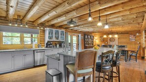 Ein rustikales Blockhaus-Interieur mit Küche, Essbereich und einer großen Holzbalkendecke.