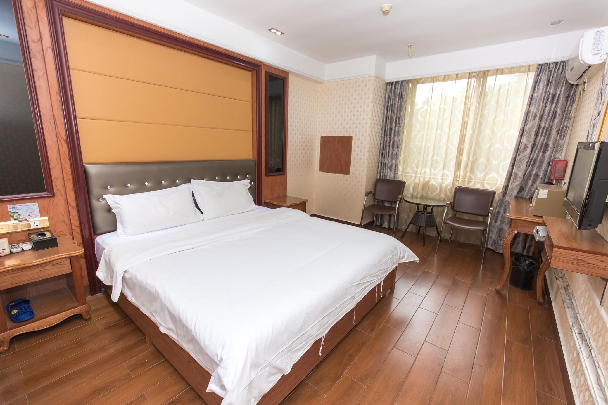 Habitación de hotel con una cama grande, un escritorio, una silla, un televisor y un cubo de basura.