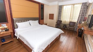 Ein Hotelzimmer mit einem großen Bett, einem Schreibtisch, einem Stuhl, einem Fernseher und einem Papierkorb.