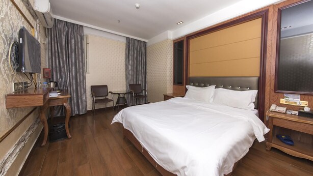 Ein Hotelzimmer mit Bett, Schreibtisch, Stuhl und Fernseher.