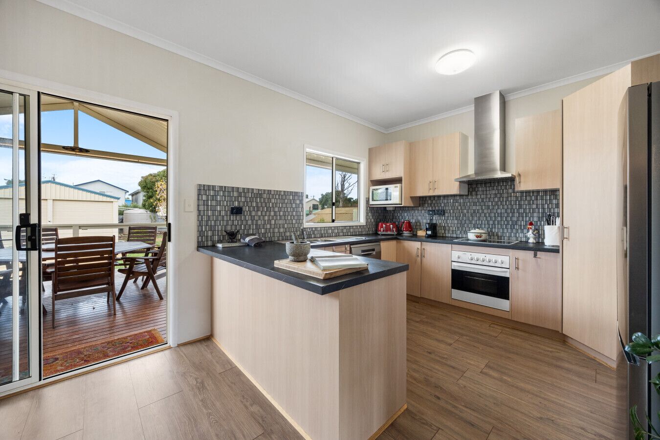 A modern kitchen with a central island, wooden cabinets, a microwave, and an oven.