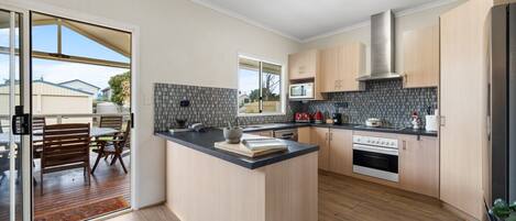 A modern kitchen with a central island, wooden cabinets, a microwave, and an oven.