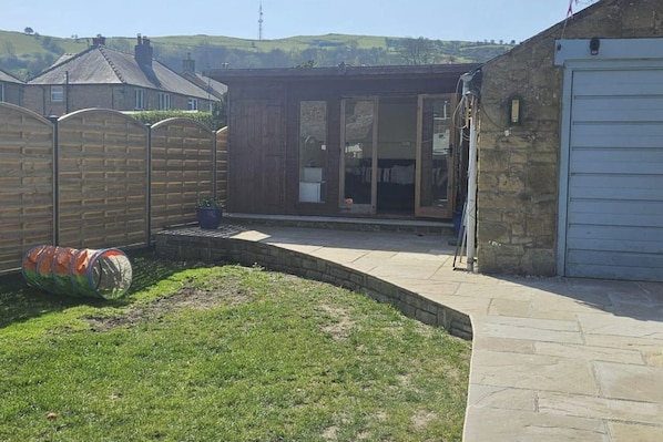 A residential backyard with a paved patio, a wooden fence, and a garage.