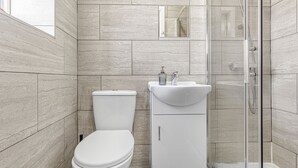 Ein modernes Badezimmer mit Toilette, Waschbecken und Duschkabine aus Glas.