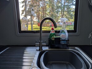 A kitchen sink with a window view of a park, a faucet, and two bottles of dish soap. - Fish Shack at Rampart - Rustic stay (Spalding)