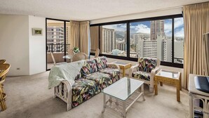 A modern hotel room with a large window, a sofa, a chair, a small table, and a cabinet. - 28th Floor Ala Moana Suite | City + Mountain Views (Honolulu)