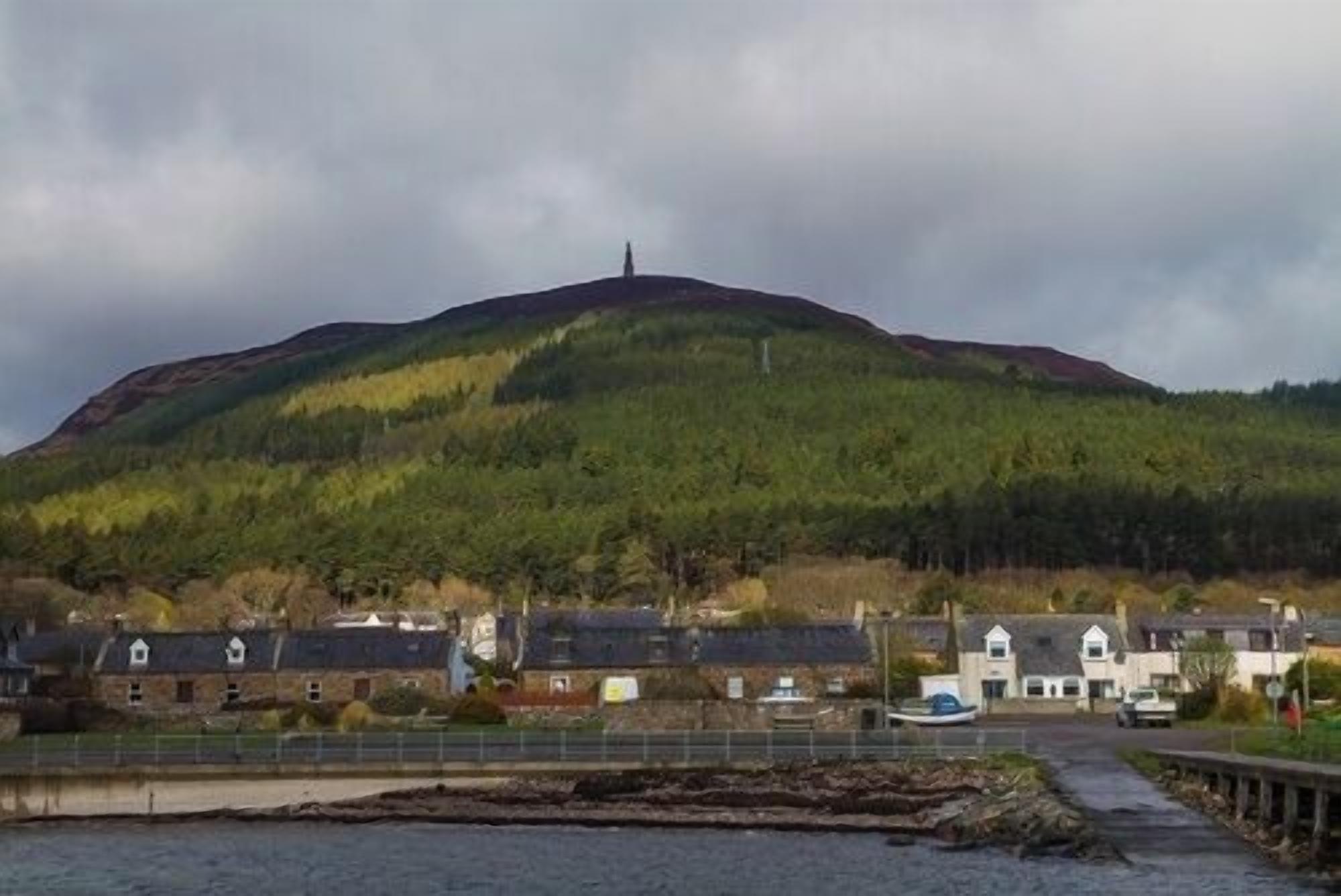 A coastal village with houses, a hill, and a body of water.