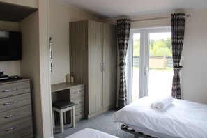 A bedroom with a bed, a desk, and a television.