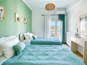 Un dormitorio con dos camas, una ventana con cortinas, un radiador y una lámpara colgante.