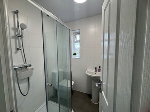 A modern bathroom with a glass-enclosed shower, a toilet, and a sink. - Apartment Sleeps 2 with Parking (Hayes)