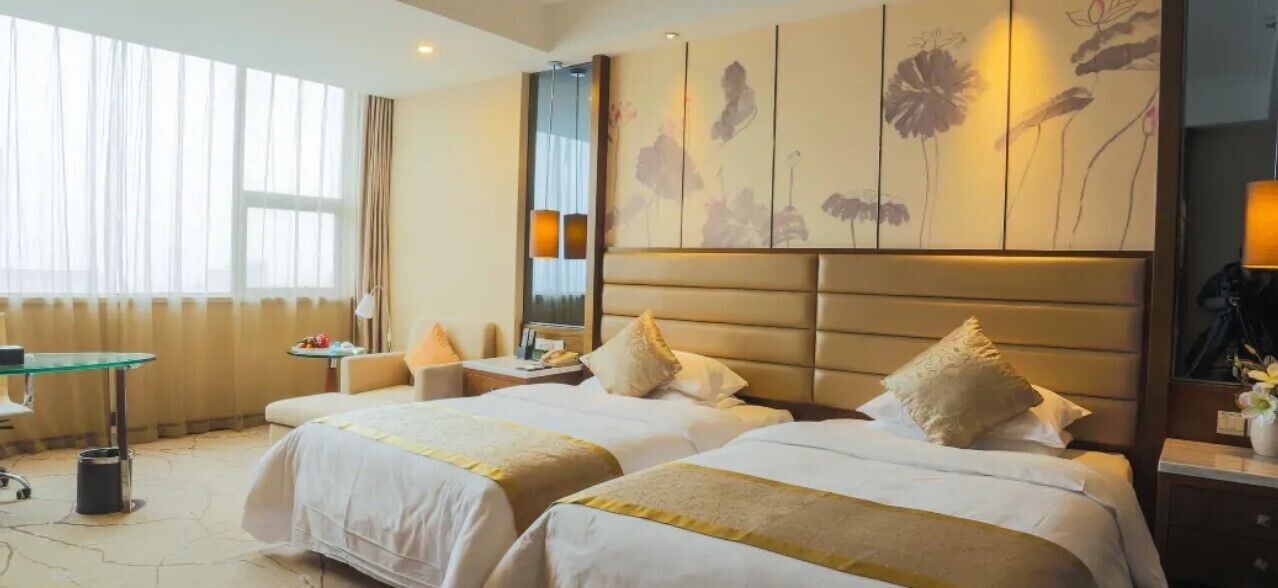 Ein Hotelzimmer mit zwei Betten, einem Schreibtisch und einem großen Fenster.