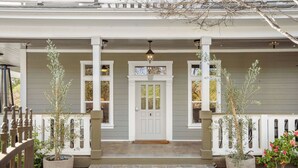 A house with a porch, a white door, and potted plants.