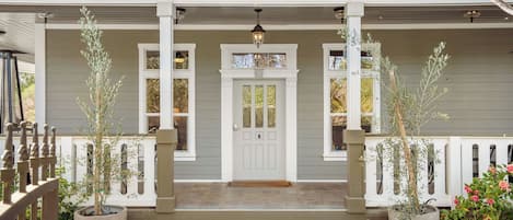 A house with a porch, a white door, and potted plants.