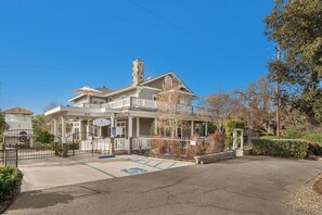 A large, two-story building with a white exterior, a stone chimney, and a covered porch.