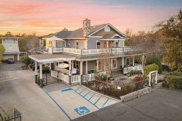 A two-story house with a balcony, a covered porch, and a parking area with handicapped accessibility.
