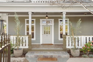 A house with a porch, a white door, and potted plants.