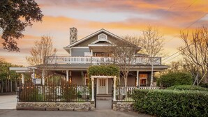 A two-story house with a porch, a stone chimney, and a gated entrance.