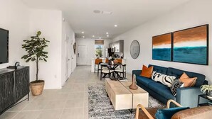 A modern living room with a sofa, coffee table, and dining area. - Furnished Model Home – Skye Ranch (Sarasota)
