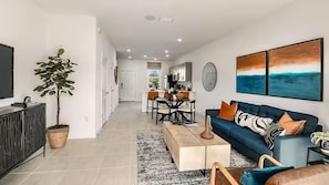 A modern living room with a sofa, coffee table, and dining area. - Furnished Model Home – Skye Ranch (Sarasota)
