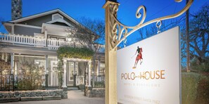 A hotel entrance with a sign for Polo-House Hotel & Bungalows, featuring a horse and rider logo.