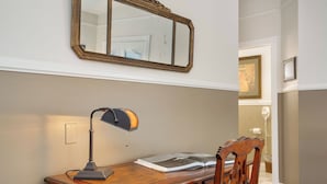 A wooden desk with a lamp, an open book, and a mirror on the wall.
