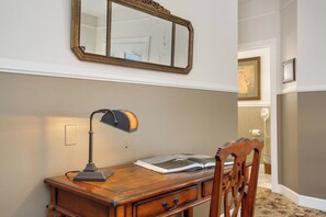 Ein Holztisch mit Lampe, einem offenen Buch und einem Spiegel an der Wand.