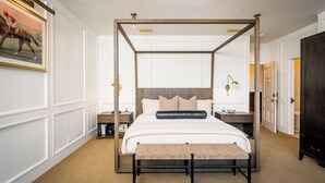 A four-poster bed with a wooden frame, a bench at the foot, and a nightstand with a lamp.