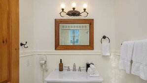 A bathroom with a white sink, a mirror, a hairdryer, and a towel rack.