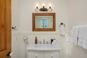 A bathroom with a white sink, a mirror, a hairdryer, and a towel rack.